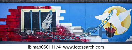 Picture - Mural Angekettete Hand makes peace sign from prison with peace dove, artist Andrej Smolák, mural at the East Side Gallery, Berlin Wall, Berlin, Germany, Europe. Fotosearch