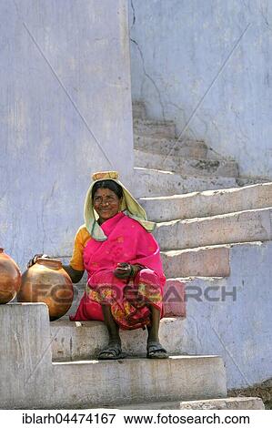 Stock Photo - Native woman with water jugs, water bearer sitting on steps, Amber Fort, Jaipur, Rajasthan, India, Asia. Fotosearch