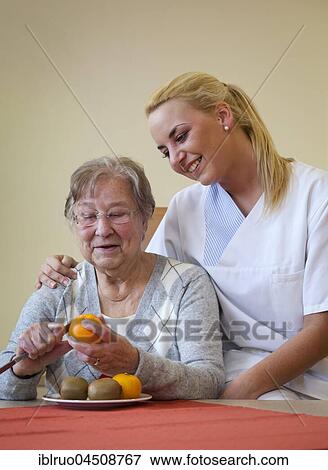 Nurse helping a senior citizen to peel fruit, Germany, Europe View Large Photo Image Stock Photo - Nurse helping a senior citizen to peel fruit, Germany, Europe. Fotosearch