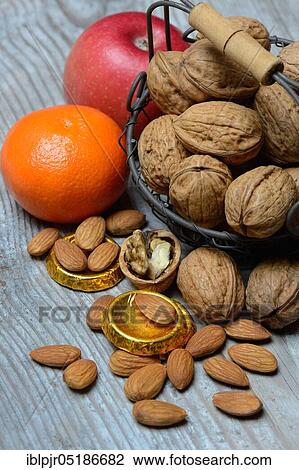 Stock Image - Nuts and fruits for St. Nicholas Day, almonds, apples, tangerine, gold coins, chocolate coins. Fotosearch