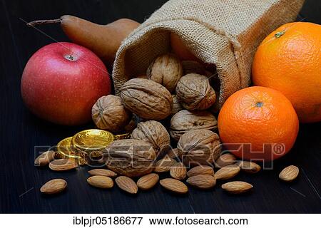 Stock Photo - Nuts and fruits for St. Nicholas Day, almonds, apples, pears, orange, tangerine, gold coins, chocolate coins. Fotosearch