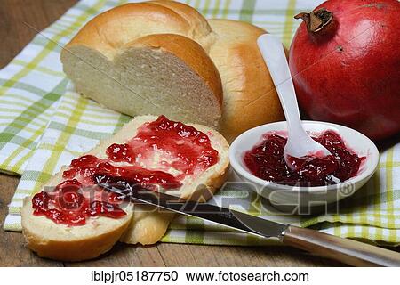 Stock Image - Pomegranate jelly on a slice of butter plait, pomegranates, Punica granatum. Fotosearch