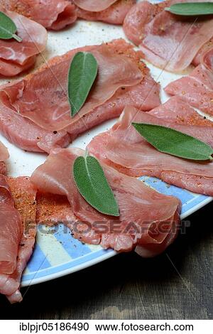 Stock Image - Preparation of Saltimbocca alla romana, Prepared escalopes with ham and sage leaves, Veal escalope, sage, sage leaf, sage leaves, Parma ham, Preparation, Veal escalope, Italy, Europe. Fotosearch