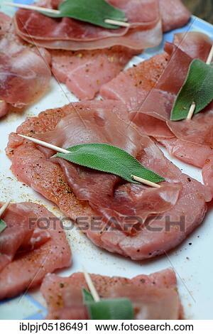 Stock Image - Preparation of Saltimbocca alla romana, Prepared escalopes with ham and sage leaves, Veal escalope, sage, sage leaf, sage leaves, Parma ham, Preparation, Veal escalope, Italy, Europe. Fotosearch