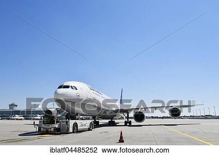 Stock Image - Push-back truck when towing the Lufthansa Airbus A340, Airport Munich, Upper Bavaria, Germany, Europe. Fotosearch