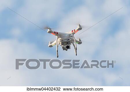 Stock Image - Quadcopter, drone with camera flying in front of blue sky, DJI Phantom 3. Fotosearch