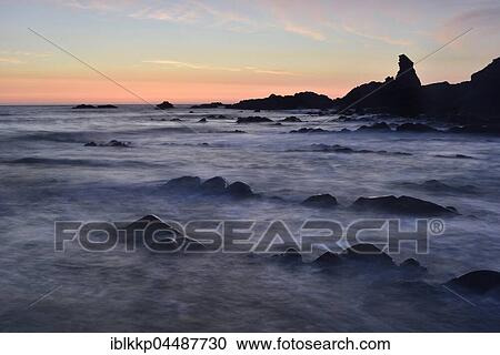Stock Image - Rocks in the sea, rocky coast in the evening light, Atlantic Coast, Hartland Quay, Devon, United Kingdom, Europe. Fotosearch