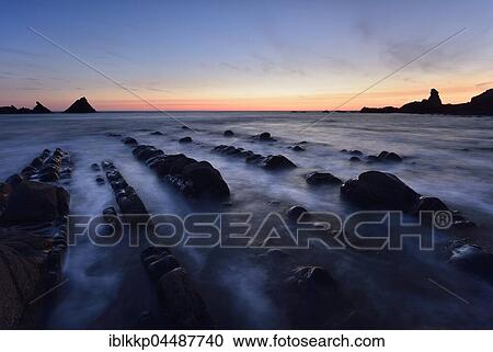 Stock Image - Rocks in the sea, rocky coast in the evening light, Atlantic Coast, Hartland Quay, Devon, United Kingdom, Europe. Fotosearch