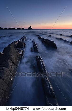 Stock Image - Rocks in the sea, rocky coast in the evening light, Atlantic Coast, Hartland Quay, Devon, United Kingdom, Europe. Fotosearch