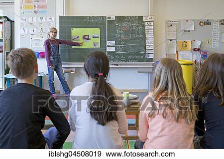 Stock Photo - Schoolgirl at the blackboard giving a presentation to fellow students, primary school, Lower Saxony, Germany, Europe. Fotosearch