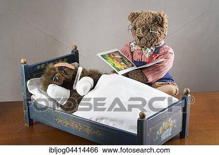 Sick Teddy Bear with bandaged paws and head, holding thermometer, in an original Pumuckl crib, Big Teddy bear in glasses and bow tie reads from book View Large Photo Image Stock Photograph - Sick Teddy Bear with bandaged paws and head, holding thermometer, in an original Pumuckl crib, Big Teddy bear in glasses and bow tie reads from book. Fotosearch