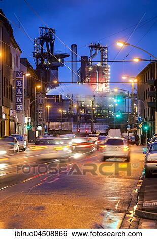 Stock Photograph - Street with cars in front of ThyssenKrupp Hüttenwerk at night, Bruckhausen, Duisburg, North Rhine-Westphalia, Germany, Europe. Fotosearch