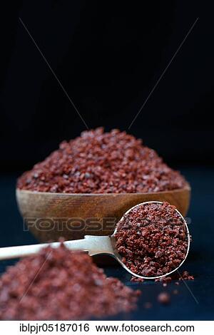 Stock Photograph - Sumac powder in wooden bowl and spoon, Rhus coriaria. Fotosearch