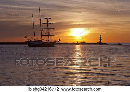 Sunset at harbor entrance, backlit sailboat, Hanse-Sail, Rostock, Mecklenburg-Western Pomerania, Germany, Europe View Large Photo Image Stock Image - Sunset at harbor entrance, backlit sailboat, Hanse-Sail, Rostock, Mecklenburg-Western Pomerania, Germany, Europe. Fotosearch