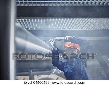 Technician, mechanic with orange helmet mounting a refrigeration line bracket, Austria, Europe View Large Photo Image Stock Photo - Technician, mechanic with orange helmet mounting a refrigeration line bracket, Austria, Europe. Fotosearch