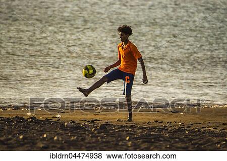 Stock Photo - Teenager playing soccer, city beach of Tarrafal, São Nicolau, Cape Verde, Africa. Fotosearch