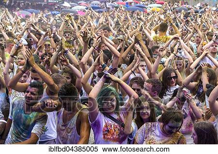 Stock Photography - Thousands of young women and man are raising their arms at the colorful Holi festival, Dresden, Saxony, Germany, Europe. Fotosearch