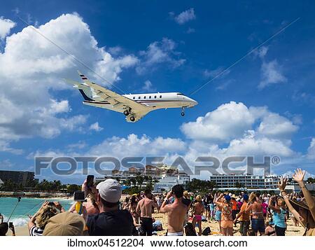 Picture - Tourists watching and photographing an airplane landing over Maho Beach, at Princess Juliana International Airport, Simson Bay Village, Philippsburg, Caribbean, Sint Maarten, North America. Fotosearch