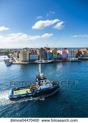 Stock Image - Tugboat, colorful row of houses in Punda district at back, commercial arcade, waterfront, World Heritage Site, Willemstad, Lesser Antilles, Curacao, South America. Fotosearch