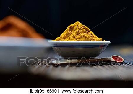 Stock Image - Turmericpowder ( Curcuma longa) in bowl and spoon. Fotosearch