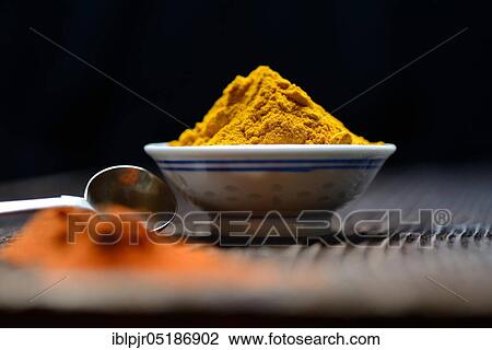 Stock Image - Turmericpowder ( Curcuma longa) in bowl and spoon. Fotosearch