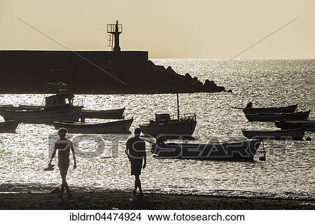 Two men on the city beach, backlight, evening mood, Port of Tarrafal, São Nicolau, Cape Verde, Africa View Large Photo Image Picture - Two men on the city beach, backlight, evening mood, Port of Tarrafal, São Nicolau, Cape Verde, Africa. Fotosearch