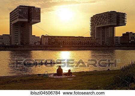 Two people picnicking on the Rhine river, crane houses at sunset, Cologne, Rhineland, North Rhine-Westphalia, Germany, Europe View Large Photo Image Picture - Two people picnicking on the Rhine river, crane houses at sunset, Cologne, Rhineland, North Rhine-Westphalia, Germany, Europe. Fotosearch