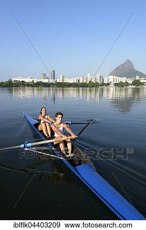 Two young women participating in early morning rowing training in the Lagoa Rodrigo de Freitas Lagoon, with Rio de Janeiro skyline and Sugar Loaf Mountain, Lagoa District, Rio de Janeiro, Brazil, South America View Large Photo Image Stock Photo - Two young women participating in early morning rowing training in the Lagoa Rodrigo de Freitas Lagoon, with Rio de Janeiro skyline and Sugar Loaf Mountain, Lagoa District, Rio de Janeiro, Brazil, South America. Fotosearch
