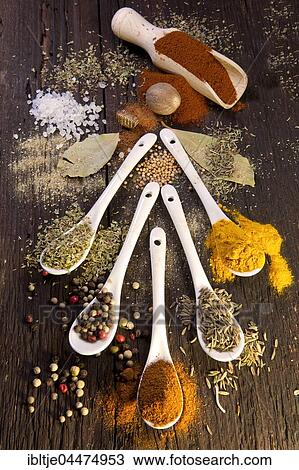 Stock Image - Various dried spices on small spoons, paprika, colorful peppercorns, basil, bay leaves, coarse salt, nutmeg, oregano, turmeric, cumin, mustard seeds. Fotosearch