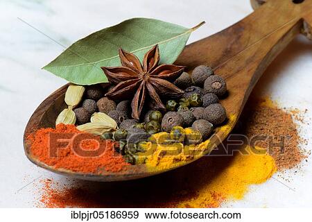 Stock Photo - Various spices in wooden spoon, paprika, chili, allspice, turmeric, star anise, cardamom, green pepper, bay leaf, nutmeg powder. Fotosearch