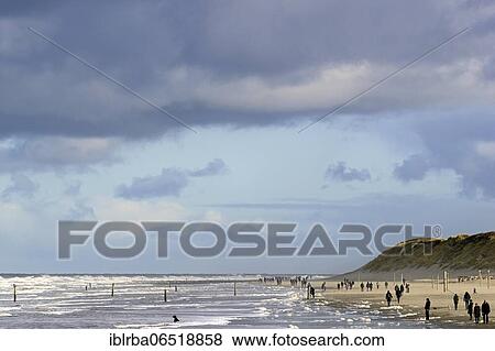 Stock Photo - View over the north beach with waves and foam formation, beach walkers at the rinse line, North Sea, Norderney, East Frisian Islands, Lower Saxony, Germany, Europe. Fotosearch