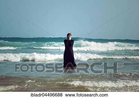 Woman in black dress with mask, standing in the surf in the sea View Large Photo Image Stock Photo - Woman in black dress with mask, standing in the surf in the sea. Fotosearch