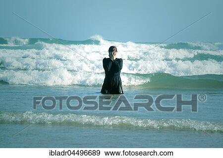 Woman in black dress with mask, standing in the surf in the sea View Large Photo Image Stock Photo - Woman in black dress with mask, standing in the surf in the sea. Fotosearch