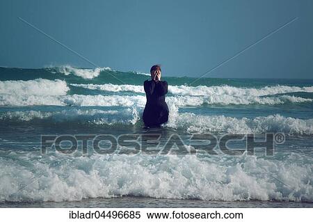 Woman in black dress with mask, standing in the surf in the sea View Large Photo Image Stock Photography - Woman in black dress with mask, standing in the surf in the sea. Fotosearch