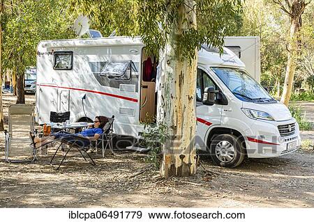 Stock Photo - Woman lying comfortably on the phone in front of a mobile home, camping ground, Bari Sardo, Provinzia di Nuoro. Sardinia (Italy). Fotosearch