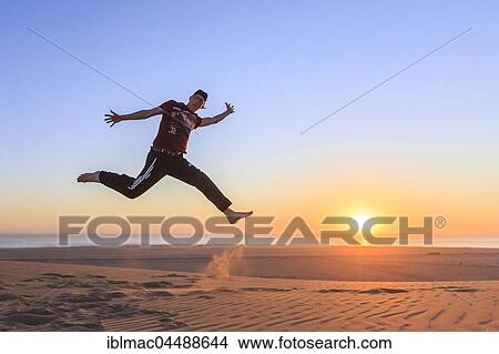 Young man jumping happily in the air, sunset, Namib desert, Langstrand, Swakopmund, Erongo Region, Namibia, Africa View Large Photo Image Picture - Young man jumping happily in the air, sunset, Namib desert, Langstrand, Swakopmund, Erongo Region, Namibia, Africa. Fotosearch
