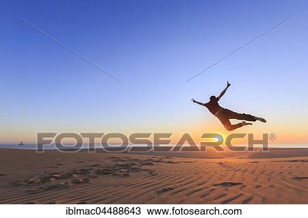 Young man jumping happily in the air, sunset, Namib desert, Langstrand, Swakopmund, Erongo Region, Namibia, Africa View Large Photo Image Stock Image - Young man jumping happily in the air, sunset, Namib desert, Langstrand, Swakopmund, Erongo Region, Namibia, Africa. Fotosearch