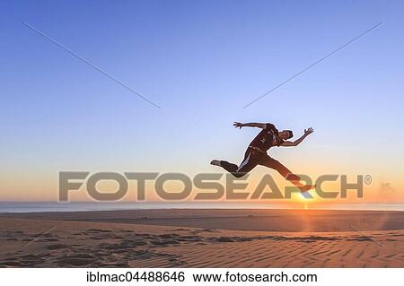 Young man jumping happily in the air, sunset, Namib desert, Langstrand, Swakopmund, Erongo Region, Namibia, Africa View Large Photo Image Stock Photograph - Young man jumping happily in the air, sunset, Namib desert, Langstrand, Swakopmund, Erongo Region, Namibia, Africa. Fotosearch