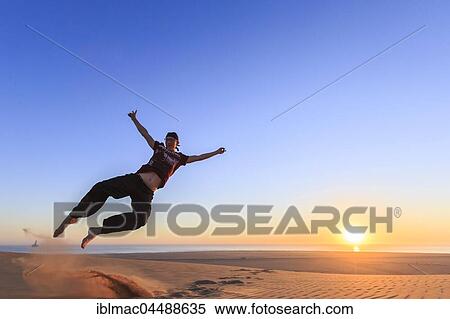 Young man jumping happily in the air, sunset, Namib desert, Langstrand, Swakopmund, Erongo Region, Namibia, Africa View Large Photo Image Stock Photography - Young man jumping happily in the air, sunset, Namib desert, Langstrand, Swakopmund, Erongo Region, Namibia, Africa. Fotosearch
