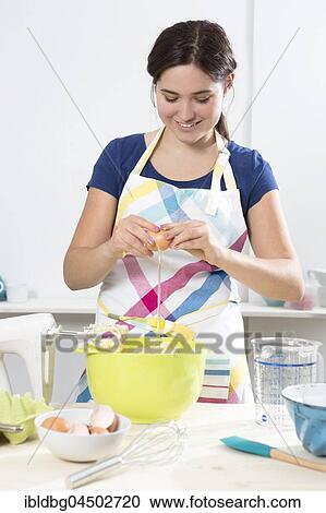 Stock Image - Young woman baking cake, separating eggs, Bavaria, Germany, Europe. Fotosearch