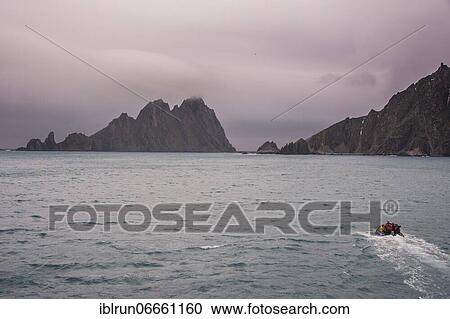 Stock Image - Zodiac with divers on its way to the rugged shore of Elephant island, South Shetland islands, Antarctica. Fotosearch