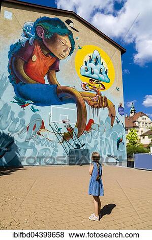 A colorful graffity with comic motive is painted at a house wall, a little girl is looking up to it, Würzburg, Bavaria, Germany, Europe View Large Photo Image Stock Photo - A colorful graffity with comic motive is painted at a house wall, a little girl is looking up to it, Würzburg, Bavaria, Germany, Europe. Fotosearch
