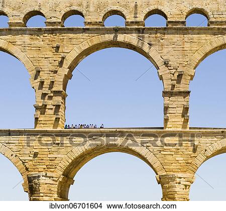 A group of tourists resting in the shadow of the Pont du Gard, Gard department, France, Europe View Large Photo Image Picture - A group of tourists resting in the shadow of the Pont du Gard, Gard department, France, Europe. Fotosearch