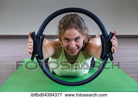A young woman is training Pilates, holding and looking through the ring, Germany, Europe View Large Photo Image Stock Photo - A young woman is training Pilates, holding and looking through the ring, Germany, Europe. Fotosearch