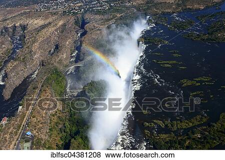 Aerial View, Zambezi river flows into the Victoria Falls waterfall with rainbow, border of Zambia and Zimbabwe, Africa View Large Photo Image Stock Photo - Aerial View, Zambezi river flows into the Victoria Falls waterfall with rainbow, border of Zambia and Zimbabwe, Africa. Fotosearch