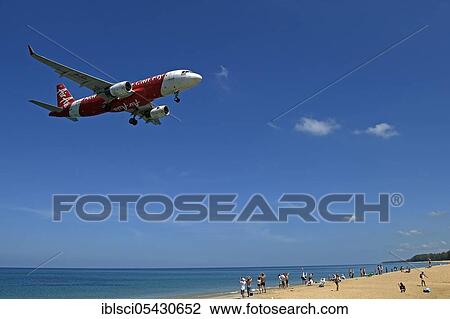 Stock Image - Air Asia aircraft, landing approach, Mai Kao Beach, Phuket, Thailand, Asia. Fotosearch
