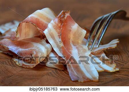 Stock Image - Bacon with fork, bacon strips, breakfast bacon. Fotosearch