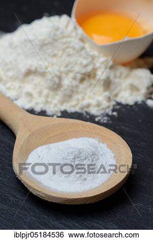 Stock Photograph - Baking powder in cooking spoon, baking ingredients, raising agent, flour, egg, chicken egg, wheat flour. Fotosearch