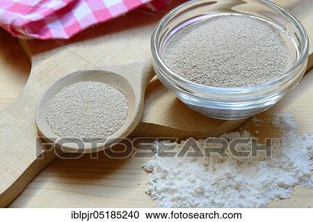 Stock Image - Baking yeast, dry yeast in spoon and bowl, baking ingredient. Fotosearch