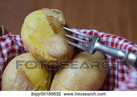 Stock Image - Boiled potatoes with fork in basket. Fotosearch